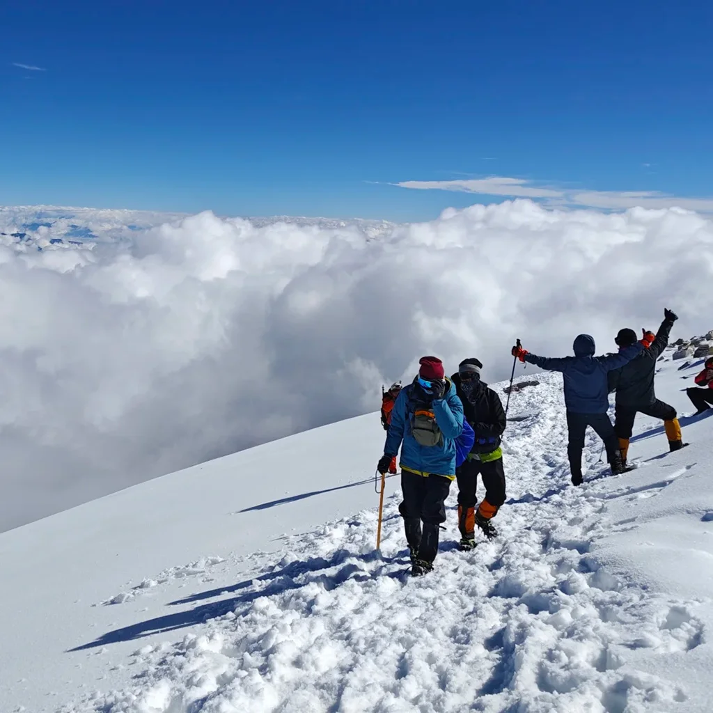 Haba Snow Mountain 在 哈巴雪山 山頂雪原上,登山者結伴前行,腳踏積雪,遠處雲海翻湧,展現壯闊高山探險景象。