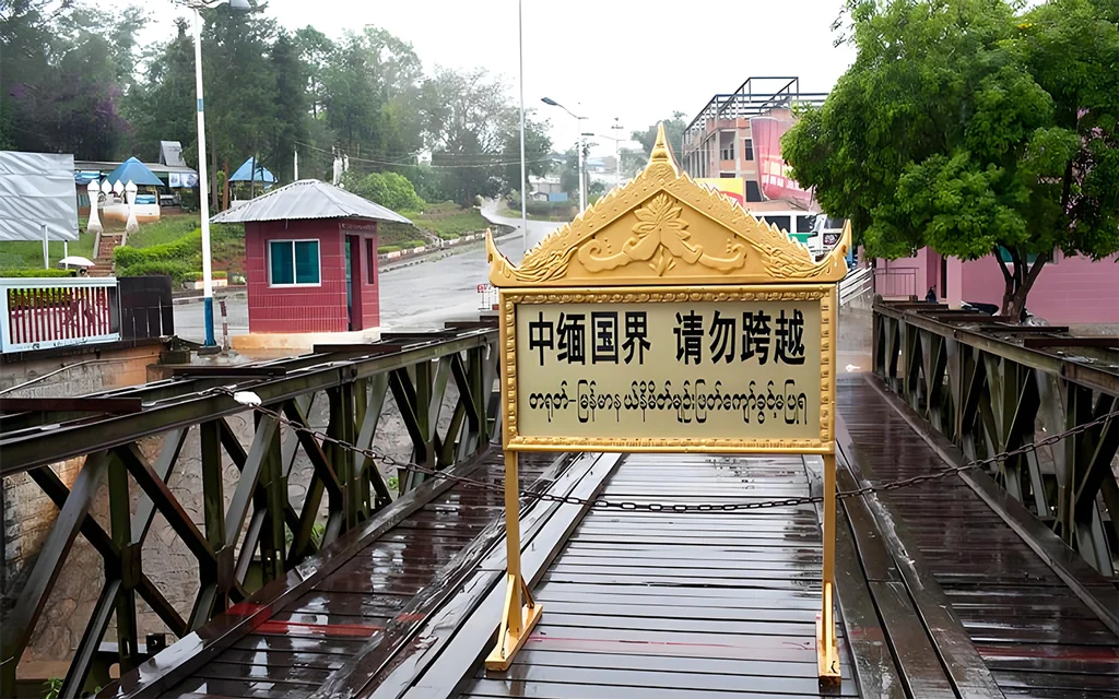 China Myanmar border 中緬邊境橋樑入口景象,橋面設有「中緬國界 請勿跨越」警示牌,周圍為邊境道路與哨所建築,展現中緬邊境地區的重要地理位置與跨國界線標誌