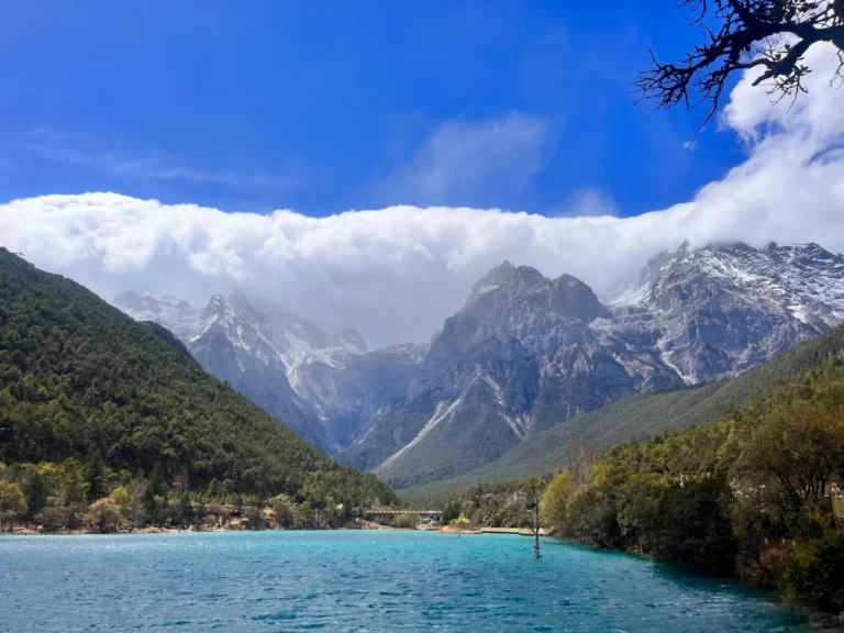 Lijiang Blue Moon Valley 1 雲南麗江藍月谷,蒂芬妮藍高山湖泊靜臥山谷之間,兩側蒼鬱山林環繞,遠處雲霧繚繞玉龍雪山積雪山巔。