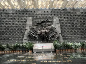 騰衝國殤墓園抗戰紀念館大廳，以中央雕塑與滿牆鋼盔為核心，再現滇西抗戰的崢嶸歲月，是對遠征軍將士的莊嚴致敬。